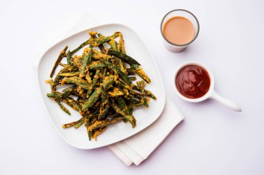 Kurkuri bhindi veya gevrek ladyfinger veya bamya kızartma tarifi, ketçap ve sıcak çay ile bir kasede servis. seçici odak