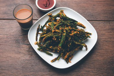 Kurkuri bhindi veya gevrek ladyfinger veya bamya kızartma tarifi, ketçap ve sıcak çay ile bir kasede servis. seçici odak