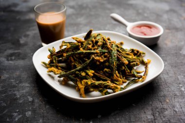 Kurkuri bhindi veya gevrek ladyfinger veya bamya kızartma tarifi, ketçap ve sıcak çay ile bir kasede servis. seçici odak