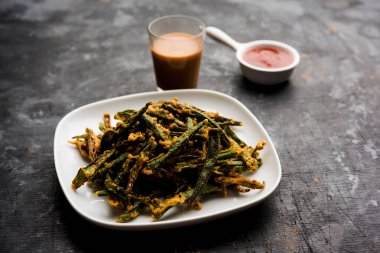 Kurkuri bhindi veya gevrek ladyfinger veya bamya kızartma tarifi, ketçap ve sıcak çay ile bir kasede servis. seçici odak