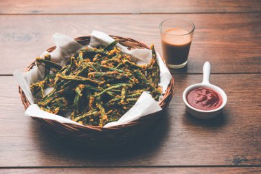 Kurkuri bhindi veya gevrek ladyfinger veya bamya kızartma tarifi, ketçap ve sıcak çay ile bir kasede servis. seçici odak