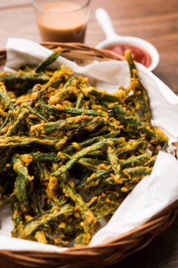Kurkuri bhindi veya gevrek ladyfinger veya bamya kızartma tarifi, ketçap ve sıcak çay ile bir kasede servis. seçici odak