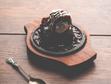 Cızırdayan çikolatalı brownie, üzerine bol bol eritilmiş çikolata dökülerek servis edilen bir top dondurmayla yapılan tatlı bir yemektir. Sunucu sıcak. seçici odak