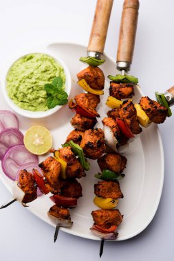 Tavuk tikka/Kebap çarpık. Geleneksel Hint yemeği kömür ve alev üzerinde pişmiş, terbiyeli ve rengarenk süslenmiş. yeşil Hint turşusu ve salata ile servis. seçici odak