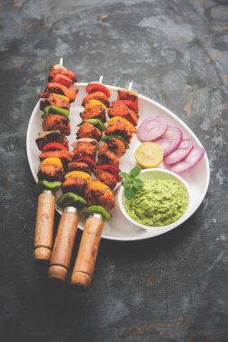 Tavuk tikka/Kebap çarpık. Geleneksel Hint yemeği kömür ve alev üzerinde pişmiş, terbiyeli ve rengarenk süslenmiş. yeşil Hint turşusu ve salata ile servis. seçici odak