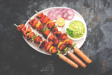 Tavuk tikka/Kebap çarpık. Geleneksel Hint yemeği kömür ve alev üzerinde pişmiş, terbiyeli ve rengarenk süslenmiş. yeşil Hint turşusu ve salata ile servis. seçici odak