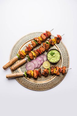 Chicken tikka /skew Kebab. Traditional Indian dish cooked on charcoal and flame, seasoned & colourfully garnished. served with green chutney and salad. selective focus clipart