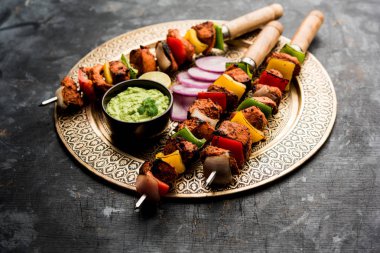 Tavuk tikka/Kebap çarpık. Geleneksel Hint yemeği kömür ve alev üzerinde pişmiş, terbiyeli ve rengarenk süslenmiş. yeşil Hint turşusu ve salata ile servis. seçici odak