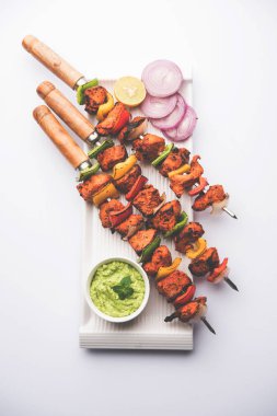 Tavuk tikka/Kebap çarpık. Geleneksel Hint yemeği kömür ve alev üzerinde pişmiş, terbiyeli ve rengarenk süslenmiş. yeşil Hint turşusu ve salata ile servis. seçici odak