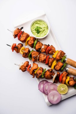 Tavuk tikka/Kebap çarpık. Geleneksel Hint yemeği kömür ve alev üzerinde pişmiş, terbiyeli ve rengarenk süslenmiş. yeşil Hint turşusu ve salata ile servis. seçici odak