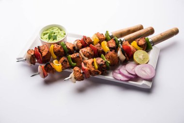 Tavuk tikka/Kebap çarpık. Geleneksel Hint yemeği kömür ve alev üzerinde pişmiş, terbiyeli ve rengarenk süslenmiş. yeşil Hint turşusu ve salata ile servis. seçici odak