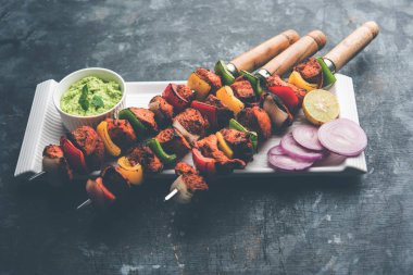 Tavuk tikka/Kebap çarpık. Geleneksel Hint yemeği kömür ve alev üzerinde pişmiş, terbiyeli ve rengarenk süslenmiş. yeşil Hint turşusu ve salata ile servis. seçici odak