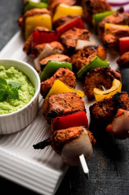Tavuk tikka/Kebap çarpık. Geleneksel Hint yemeği kömür ve alev üzerinde pişmiş, terbiyeli ve rengarenk süslenmiş. yeşil Hint turşusu ve salata ile servis. seçici odak