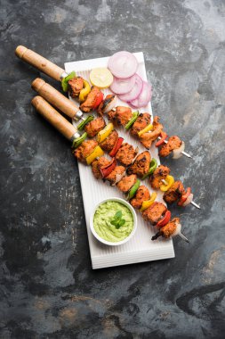 Tavuk tikka/Kebap çarpık. Geleneksel Hint yemeği kömür ve alev üzerinde pişmiş, terbiyeli ve rengarenk süslenmiş. yeşil Hint turşusu ve salata ile servis. seçici odak