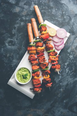 Tavuk tikka/Kebap çarpık. Geleneksel Hint yemeği kömür ve alev üzerinde pişmiş, terbiyeli ve rengarenk süslenmiş. yeşil Hint turşusu ve salata ile servis. seçici odak