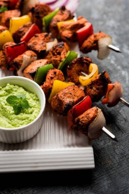 Tavuk tikka/Kebap çarpık. Geleneksel Hint yemeği kömür ve alev üzerinde pişmiş, terbiyeli ve rengarenk süslenmiş. yeşil Hint turşusu ve salata ile servis. seçici odak