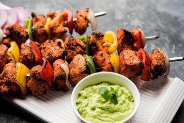Tavuk tikka/Kebap çarpık. Geleneksel Hint yemeği kömür ve alev üzerinde pişmiş, terbiyeli ve rengarenk süslenmiş. yeşil Hint turşusu ve salata ile servis. seçici odak