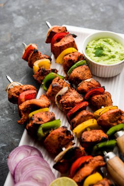 Tavuk tikka/Kebap çarpık. Geleneksel Hint yemeği kömür ve alev üzerinde pişmiş, terbiyeli ve rengarenk süslenmiş. yeşil Hint turşusu ve salata ile servis. seçici odak