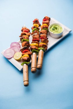 Tavuk tikka/Kebap çarpık. Geleneksel Hint yemeği kömür ve alev üzerinde pişmiş, terbiyeli ve rengarenk süslenmiş. yeşil Hint turşusu ve salata ile servis. seçici odak