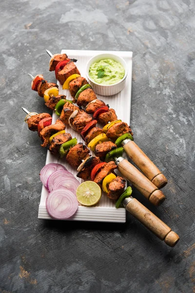 チキンティッカ ケバブを傾斜させます 伝統的なインド料理は 炭と炎で調理 味付け カラフル添え 緑のチャツネとサラダを添えてください 選択と集中 — ストック写真