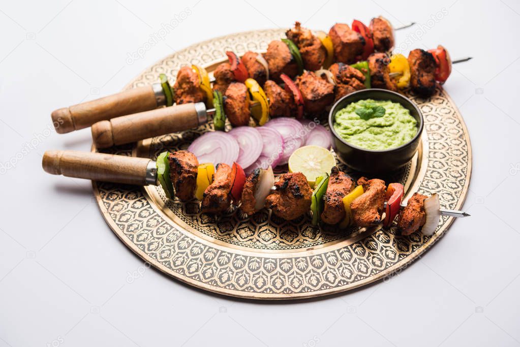 Chicken tikka /skew Kebab. Traditional Indian dish cooked on charcoal and flame, seasoned & colourfully garnished. served with green chutney and salad. selective focus