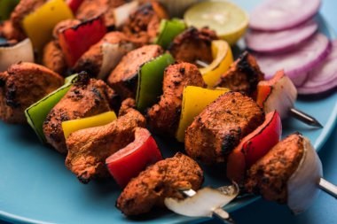 ızgara tavuk tikka şiş üzerinde. bir tabak yeşil Hint turşusu ve soğan ile servis. Seçici odak