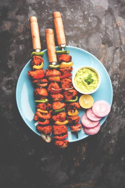 ızgara tavuk tikka şiş üzerinde. bir tabak yeşil Hint turşusu ve soğan ile servis. Seçici odak