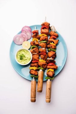 ızgara tavuk tikka şiş üzerinde. bir tabak yeşil Hint turşusu ve soğan ile servis. Seçici odak