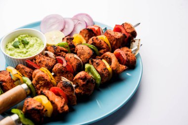 ızgara tavuk tikka şiş üzerinde. bir tabak yeşil Hint turşusu ve soğan ile servis. Seçici odak