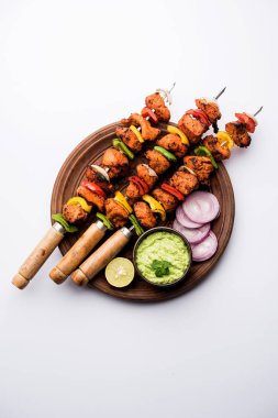 ızgara tavuk tikka şiş üzerinde. bir tabak yeşil Hint turşusu ve soğan ile servis. Seçici odak