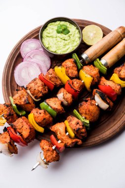 ızgara tavuk tikka şiş üzerinde. bir tabak yeşil Hint turşusu ve soğan ile servis. Seçici odak