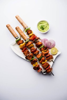 ızgara tavuk tikka şiş üzerinde. bir tabak yeşil Hint turşusu ve soğan ile servis. Seçici odak