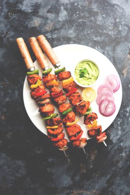 ızgara tavuk tikka şiş üzerinde. bir tabak yeşil Hint turşusu ve soğan ile servis. Seçici odak