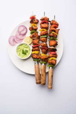 ızgara tavuk tikka şiş üzerinde. bir tabak yeşil Hint turşusu ve soğan ile servis. Seçici odak