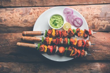 ızgara tavuk tikka şiş üzerinde. bir tabak yeşil Hint turşusu ve soğan ile servis. Seçici odak