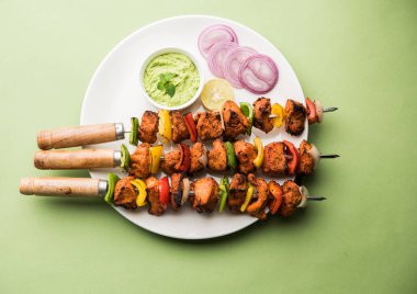 ızgara tavuk tikka şiş üzerinde. bir tabak yeşil Hint turşusu ve soğan ile servis. Seçici odak