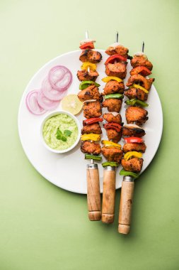 ızgara tavuk tikka şiş üzerinde. bir tabak yeşil Hint turşusu ve soğan ile servis. Seçici odak