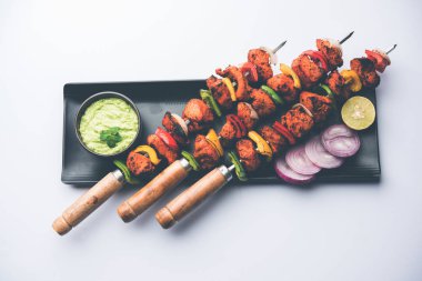 ızgara tavuk tikka şiş üzerinde. bir tabak yeşil Hint turşusu ve soğan ile servis. Seçici odak