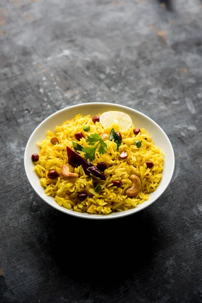 Lemon Rice is a South Indian turmeric rice or maharashtrian recipe called fodnicha bhat using leftover rice garnished with nuts curry leaves and lemon juice, selective focus