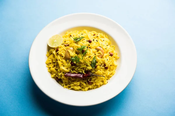 Lemon Rice is a South Indian turmeric rice or maharashtrian recipe called fodnicha bhat using leftover rice garnished with nuts curry leaves and lemon juice, selective focus