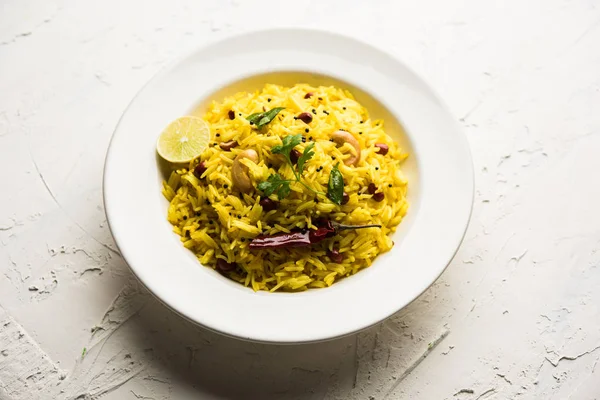 Lemon Rice is a South Indian turmeric rice or maharashtrian recipe called fodnicha bhat using leftover rice garnished with nuts curry leaves and lemon juice, selective focus