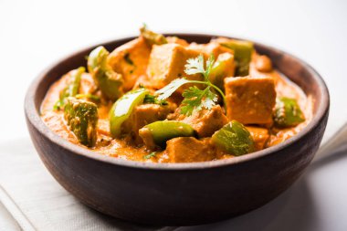 Malai or achari Paneer in a gravy made using red gravy and green capsicum. served in a bowl. selective focus clipart