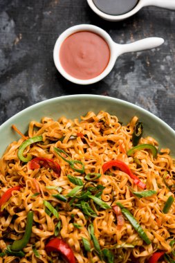 Schezwan veg noodles is a spicy and tasty stir fried flat Hakka noodles with sauce and veggies. served with chopsticks. selective focus clipart