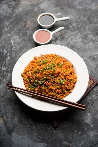 Schezwan 揚げ米マサラは箸で皿やボウルでお召し上がりいただけます人気のインド中華料理です 選択と集中 — ストック写真