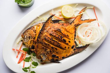 Tandır Pomfret balık kil fırında pişmiş ve limon, nane, lahana ve havuç salatası ile süslenmiş. Seçici odak