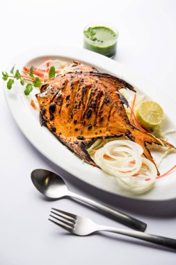 Tandır Pomfret balık kil fırında pişmiş ve limon, nane, lahana ve havuç salatası ile süslenmiş. Seçici odak