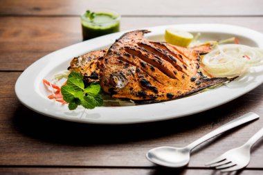 Tandır Pomfret balık kil fırında pişmiş ve limon, nane, lahana ve havuç salatası ile süslenmiş. Seçici odak