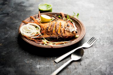 Tandır Pomfret balık kil fırında pişmiş ve limon, nane, lahana ve havuç salatası ile süslenmiş. Seçici odak