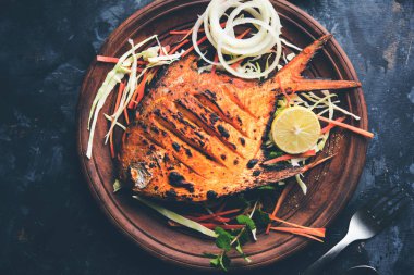 Tandır Pomfret balık kil fırında pişmiş ve limon, nane, lahana ve havuç salatası ile süslenmiş. Seçici odak