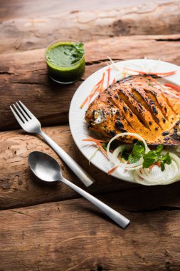 Tandır Pomfret balık kil fırında pişmiş ve limon, nane, lahana ve havuç salatası ile süslenmiş. Seçici odak